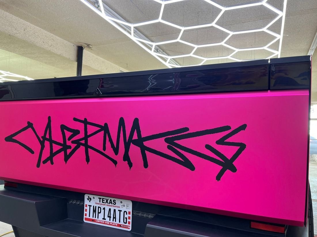 Hot pink matte wrap on a Cybertruck tailgate with black graffiti lettering